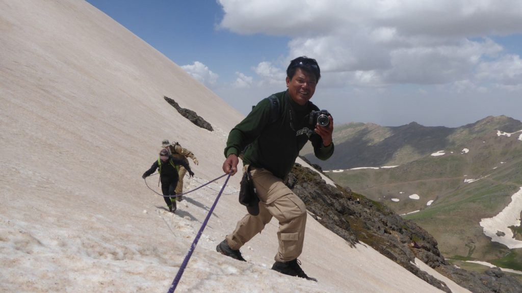 Zau Seng crosses the snow field, camera in hand.