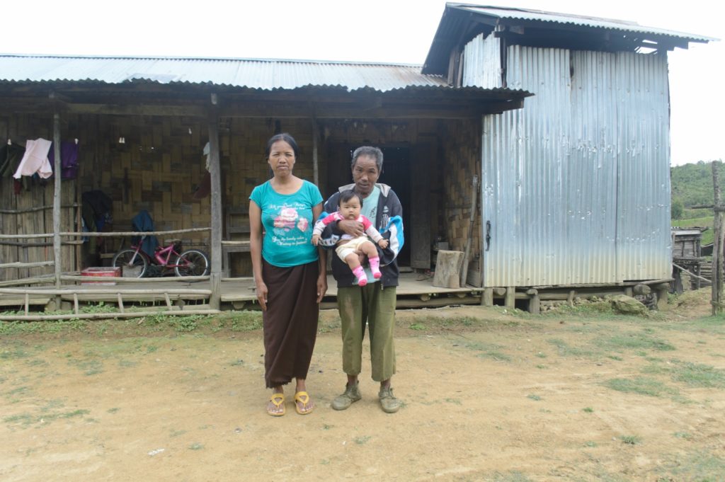 Local family outside their corrugated metal dwelling, Chin state. 