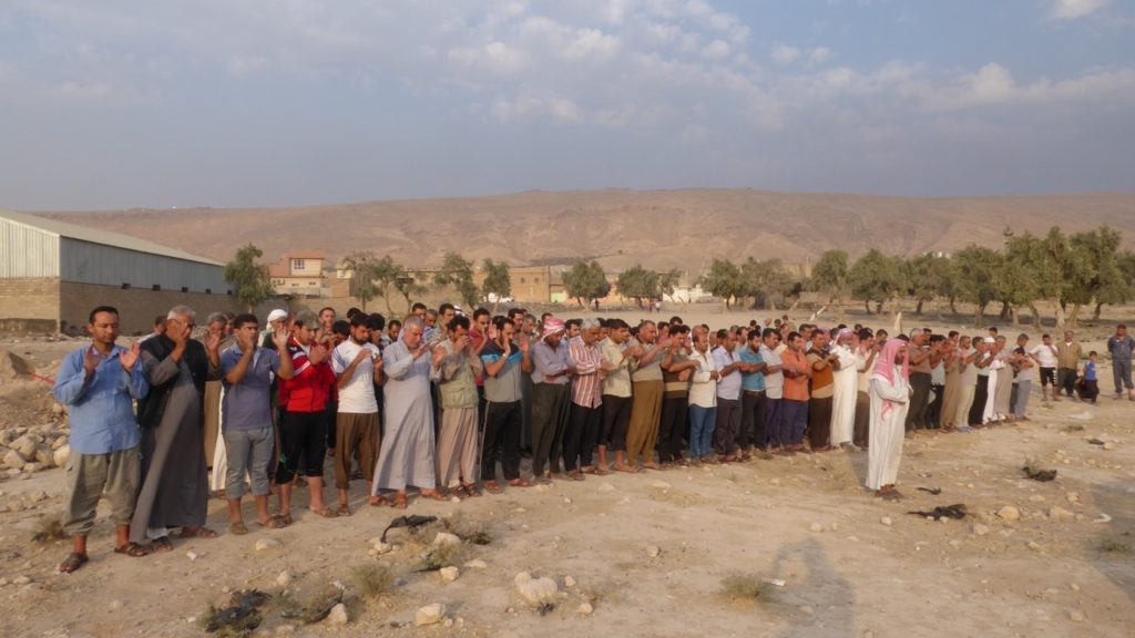 Townsmen praying before the burial.