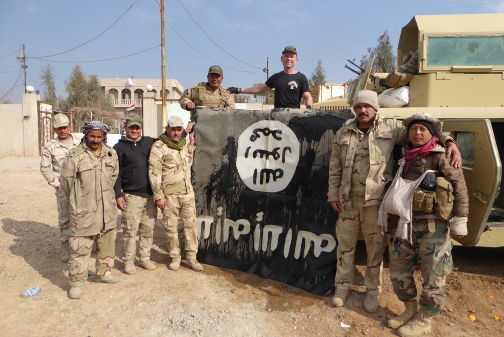 Eliya (far right) with ISIS flag our team captured outside of Mosul 