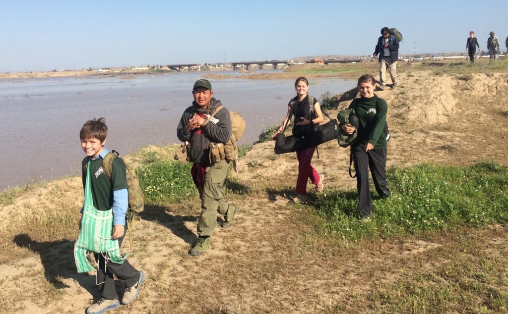 Walking to the boat along the Tigris after Easter sunrise service with submerged bridge and blown bridge in the background