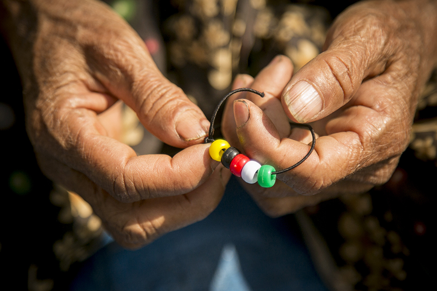 The weathered hands of an opium farmer hold a bracelet with colored beads representing the Christian story of forgiveness and hope, given to her during a Good Life Program for women and children organized during a relief mission to northern Shan State, Burma. (February 2015)