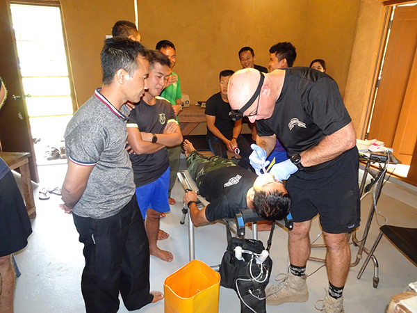 Shannon demonstrating dental procedures to JSMK medics as he fills a tooth.