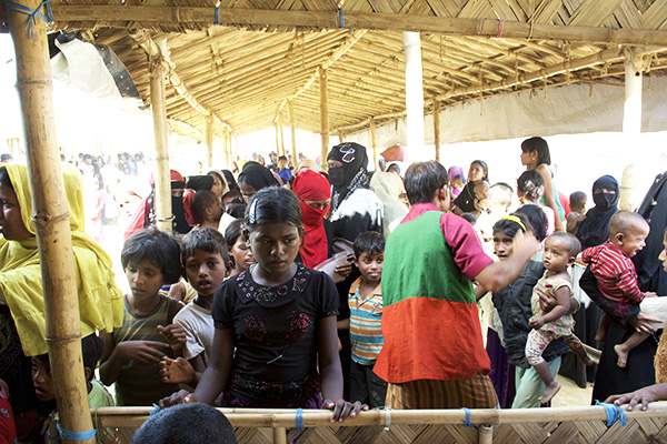 A young Rohingya girl waits to have her supply card checked at a distribution inside one of the refugee camps. 