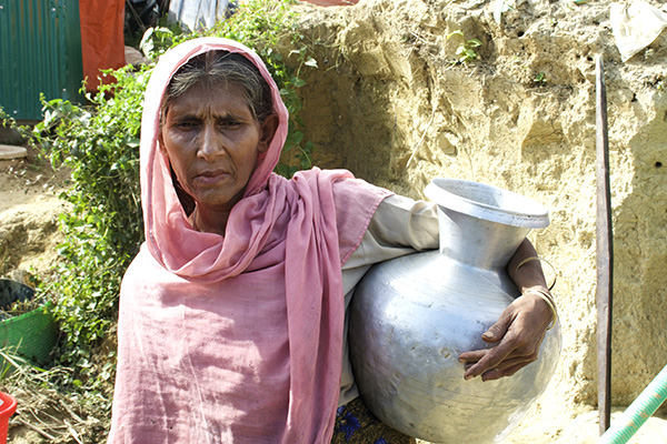 A Rohingya woman carries her water jug from a collection point in one of the refugee camps. Despite improvements in infrastructure, the camps are not a sustainable living option for the 700,000 Rohingya who have fled Burma Army oppression.