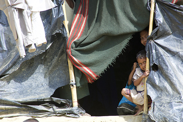 A Rohingya family peeks out of their temporary housing in one of Bangladesh's many refugee camps. 