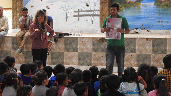 Karen and Bashir share with Yezidis who fled Afrin in the fellowship hall damaged by machine guns.