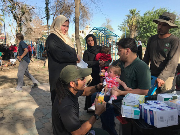 Karen medic Joseph giving medicine to families at the makeshift clinic in the park, Raqqa. 