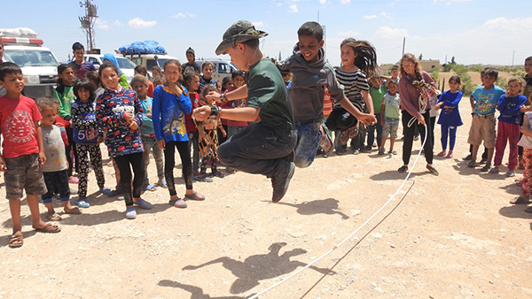 Pete jump ropes with Arab children near Menbij during a Good Life Club program
