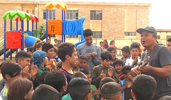 Eliya, a Karen medic, leads kids in song at a new playground built with help from Reload Love