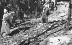 villagers sift through remains of burned home