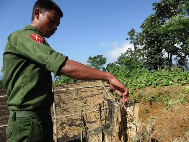 A KIA soldier points to a splintered building foundation destroyed by Burmese explosives. 
