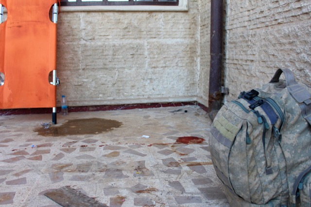 Riley’s medical bag rests outside the school they used as a emergency care center, ready to go and help if needed. The blood of several patients pools on the ground nearby.