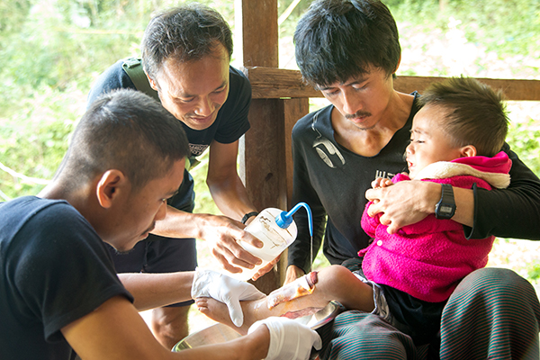 JSMK medics work to drain the abscess and change the dressing on the young patient.