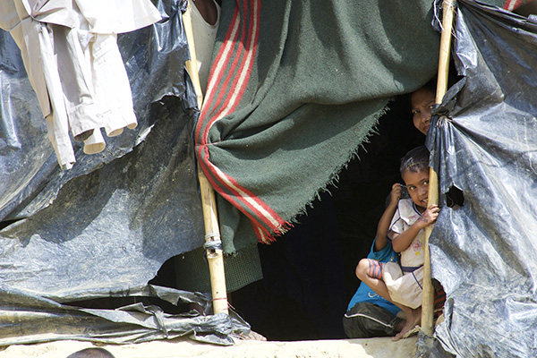 A Rohingya family peeks out of their temporary housing in one of Bangladesh's many refugee camps.