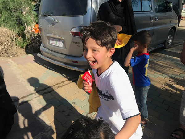 An excited young boy makes off with a shirt and snack. 