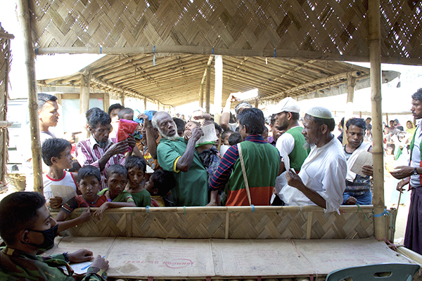 Rohingya men jostle for a spot at the front of a line during a distribution in one of the many refugee camps.