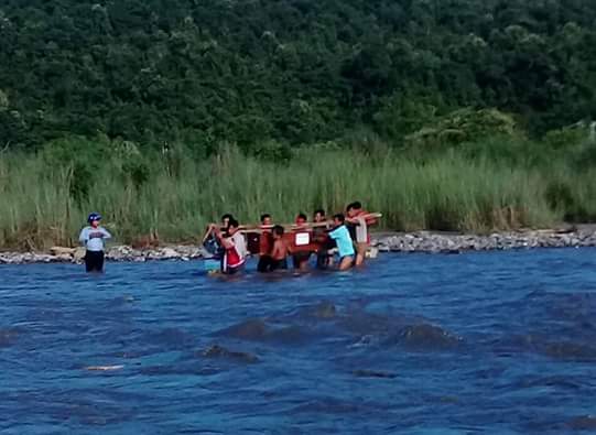 The burial party is forced to ford the river with Mr. Khwe Mana’s coffin.