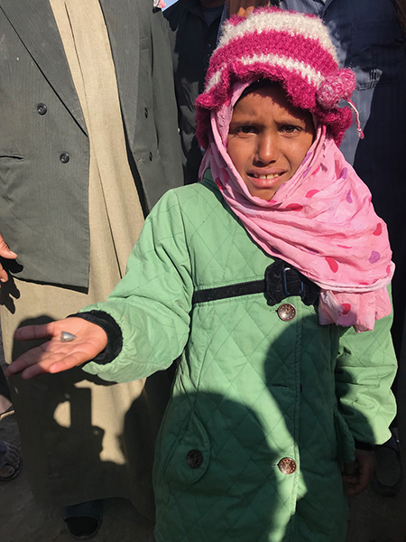 Near Hajin, a girl holds out the ISIS bullet that wounded her.