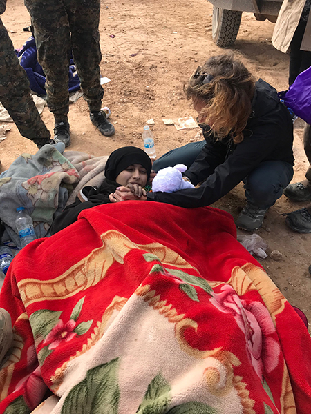 Karen prays with a badly wounded girl as she gives her a stuffed lamb.