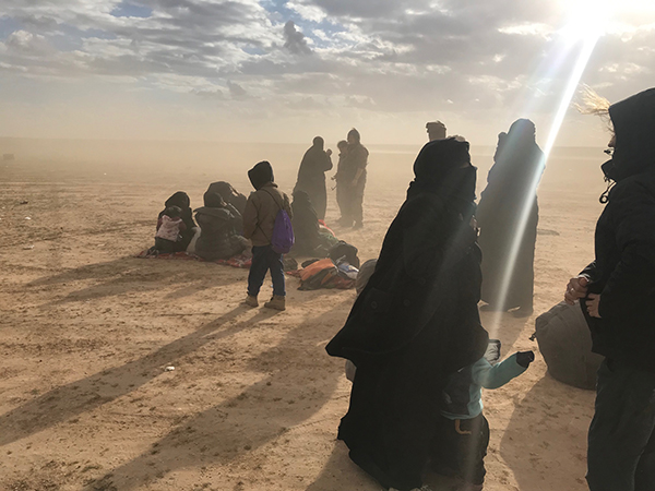 The families are met with dust and freezing wind as they flee ISIS and wait for transport. 