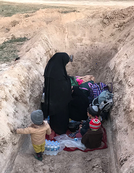 A family takes shelter in a ditch after fleeing.