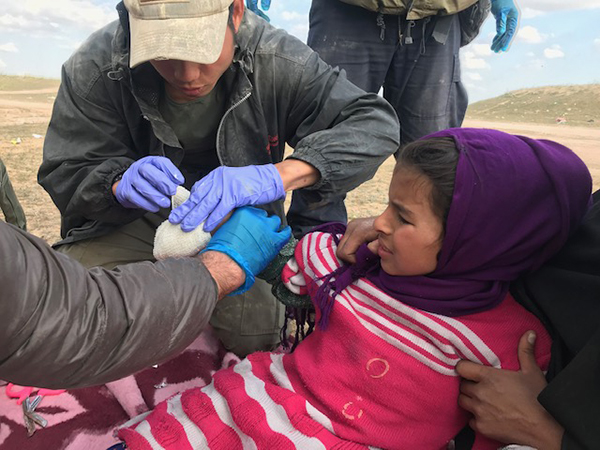 Joseph, a Karen medic, treats a girl injured by ISIS