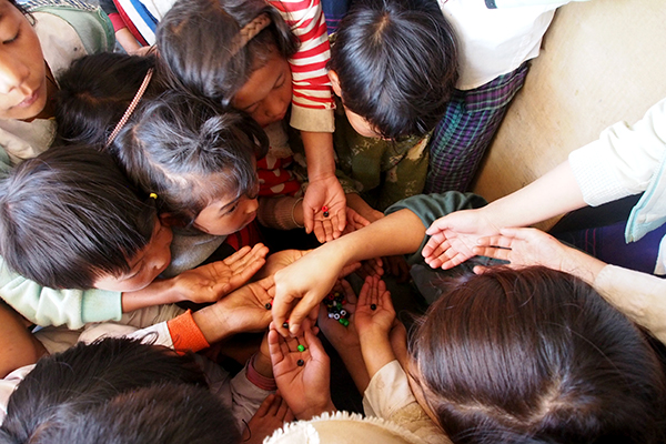 IDP children receive beads to make their GLC bracelets.