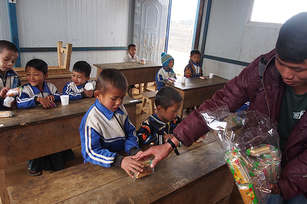 A Ranger gives out snacks to IDP children.