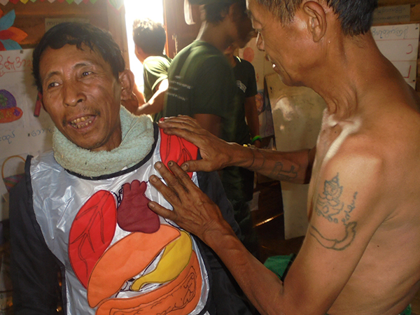 Local villagers play with an anatomy apron which is usually worn by children during a GLC program to learn about the functions of major organs and keeping them healthy.
