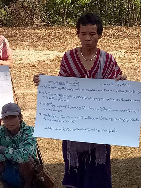 A villager holds up a sign protesting the Burma Army building a road and bridge in Karen State.