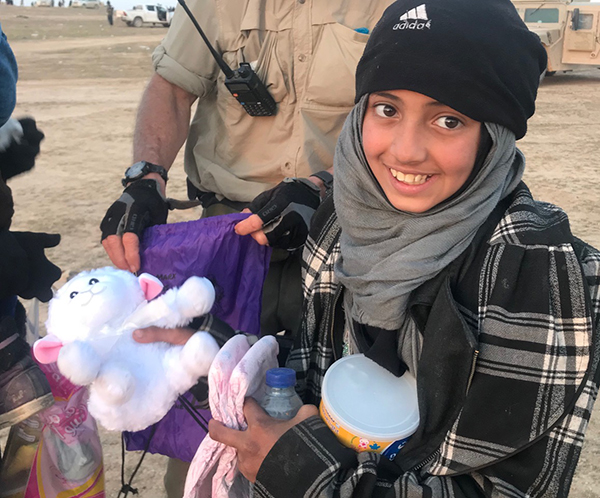 A girl holds her new lamb toy from All Things Possible Ministries.