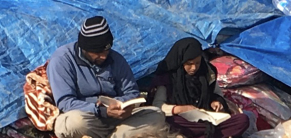 A father and daughter who escaped ISIS read new bibles given to them by the team.