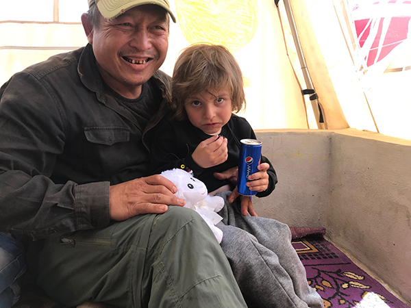 Eliya gives a stuffed lamb from ATP Ministries to a new friend in Al-Hawl.