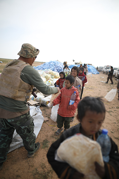 Zau Seng distributing food and water to ISIS children who had just fled Baghouz, Syria.