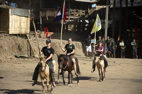 Suu, Sahale, and Peter open the TUW Camp Olympics by carrying the flame, Karen flag, and the flag for northeast Syria