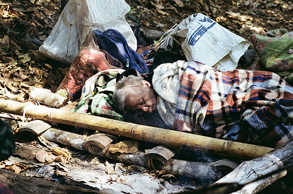 A Karen Grandmother who suffered from a stroke and can no longer sit up or stand sleeps on the jungle floor