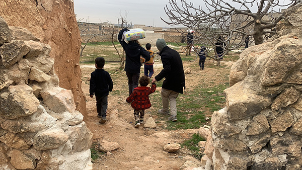 Families bring the food back to abandoned homes they are staying in outside Manbij