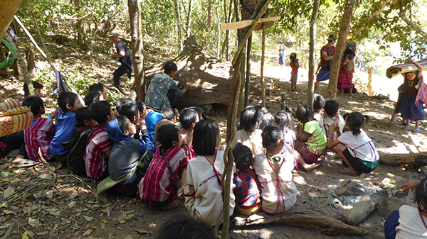 School continues in the jungle by using a fallen tree as a chalkboard