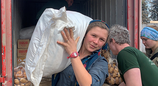 Suu, Miles and Sahale carry food to the displaced