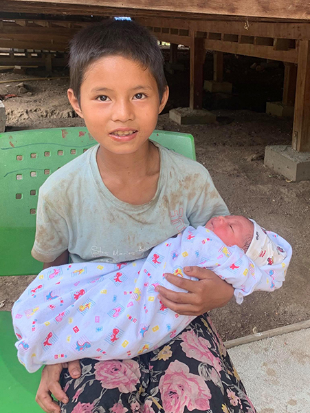 Sister holding her new baby brother at JSMK